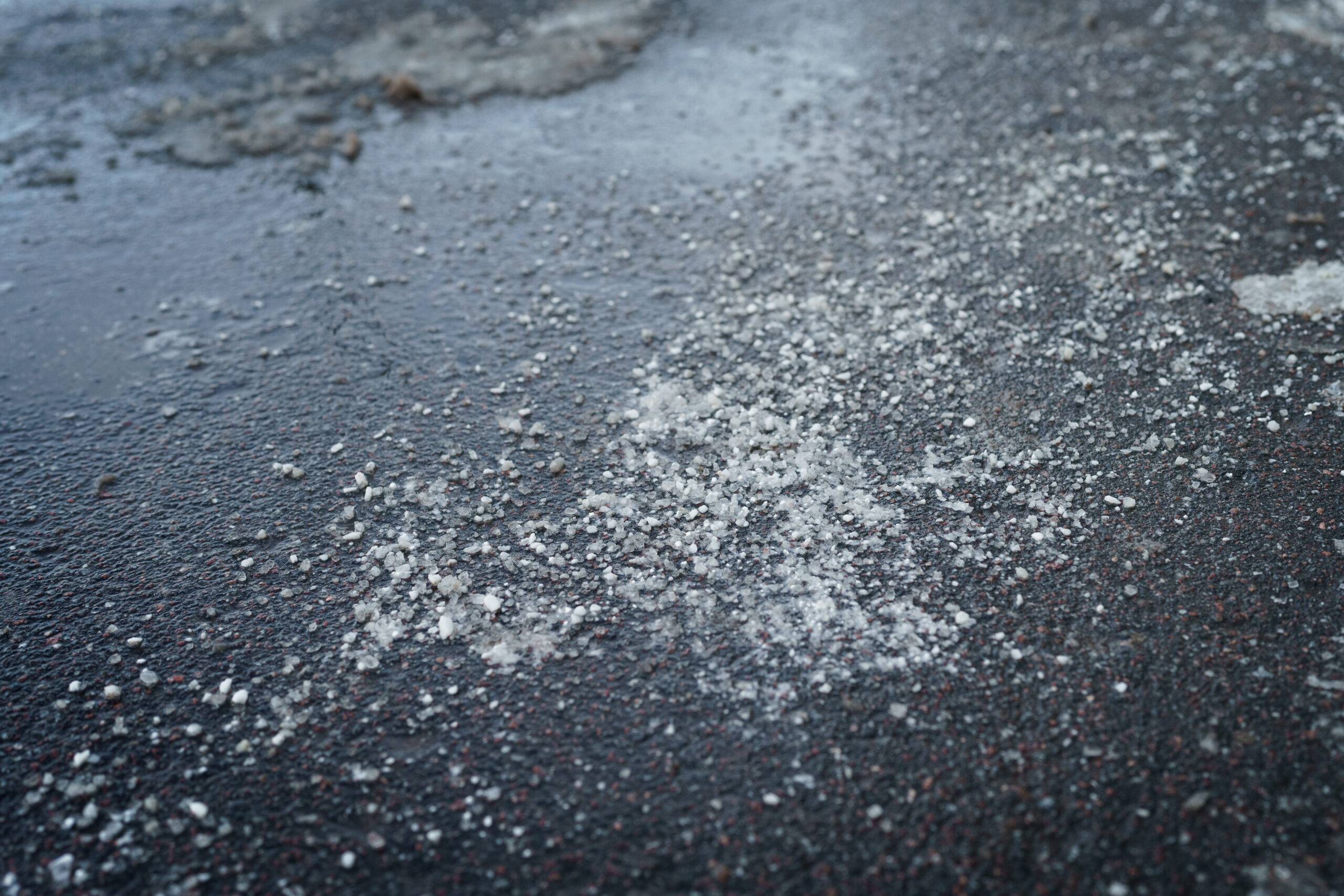 De-icing chemicals reagent on asp&aring;halt. Pavement is sprinkled with technical salt or salt mixtures based on it. Effective tool to fight ice on roads in winter season. .