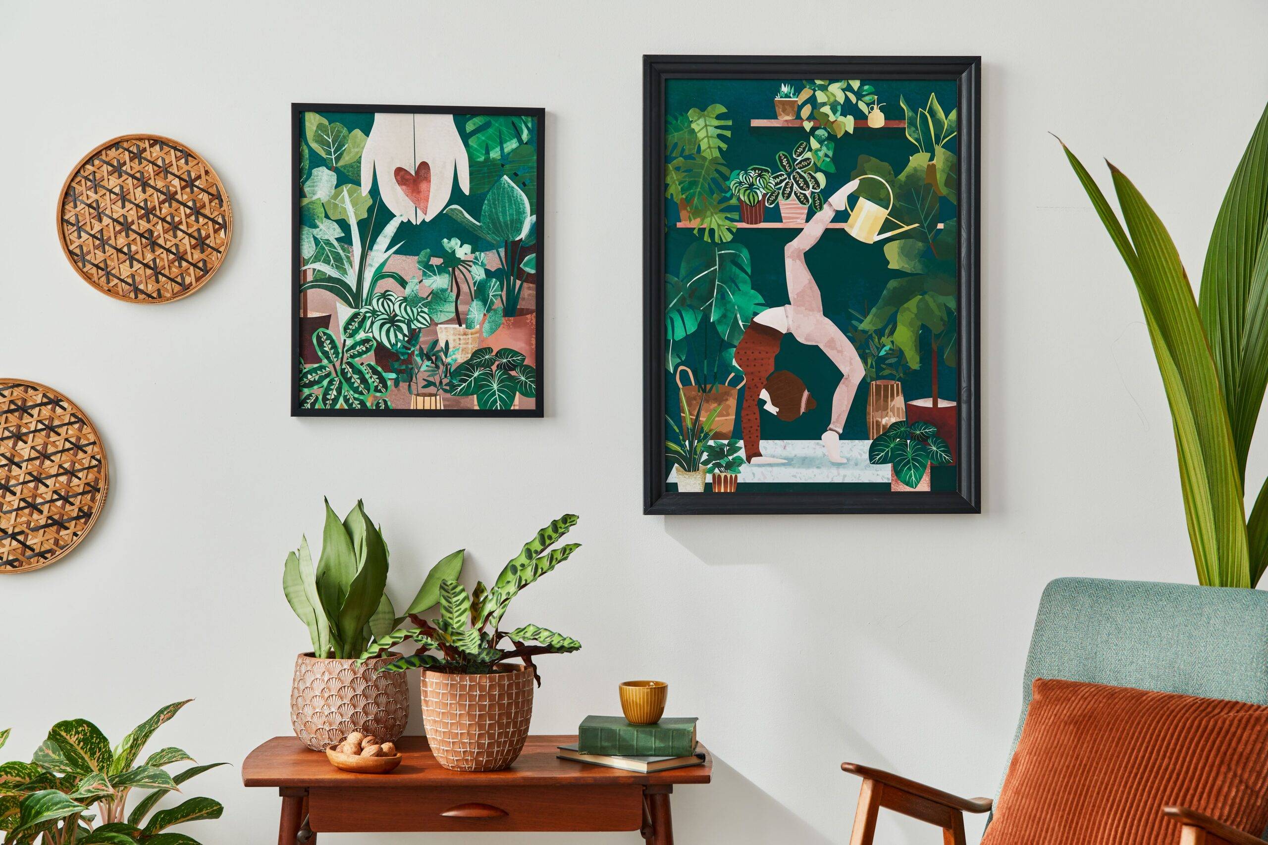 Green, plant-related art hung on a wall above a table with some houseplants.