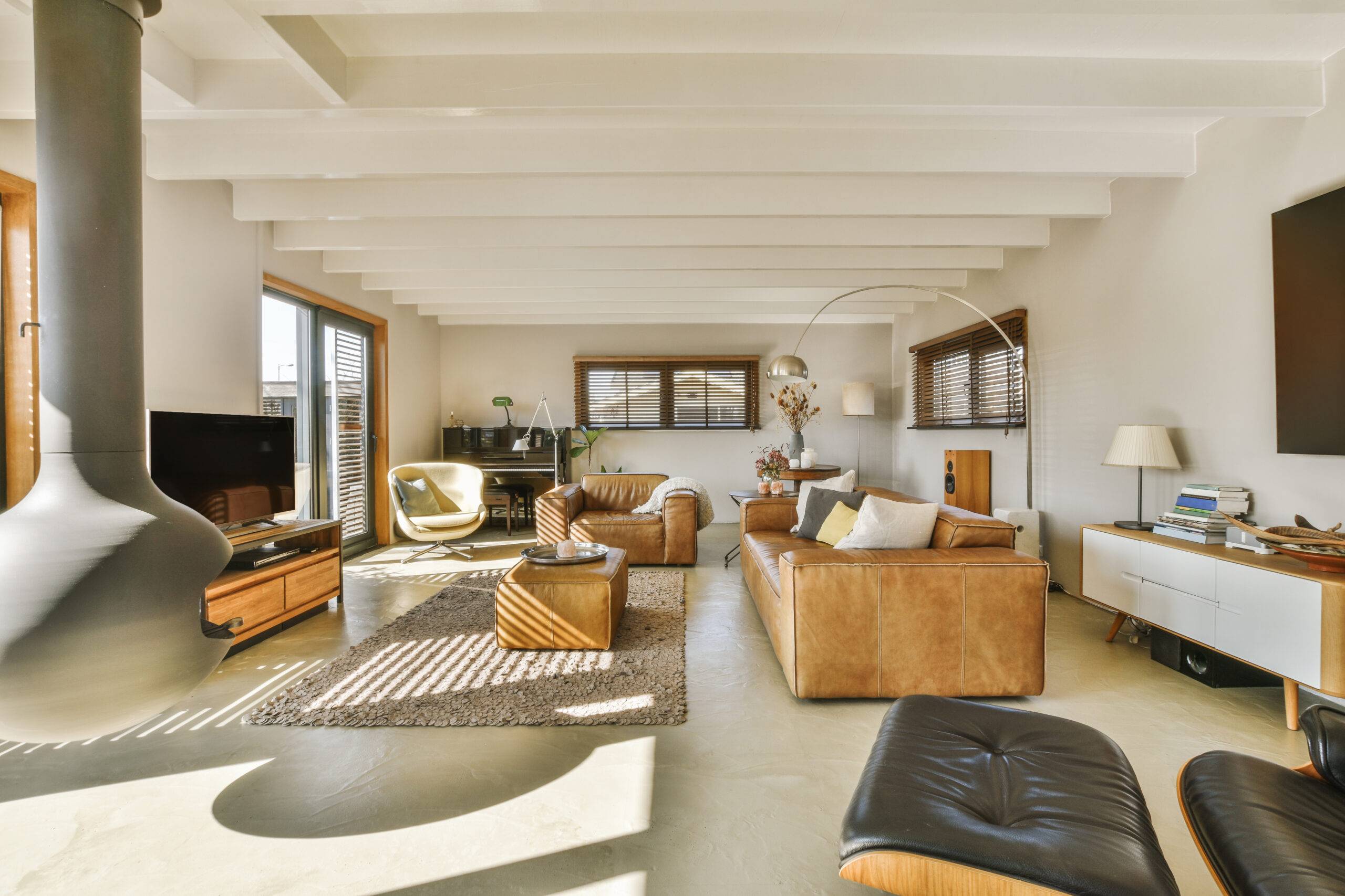 Comfortable sofa with cushions placed against light wall with TV and decorations in modern loving room