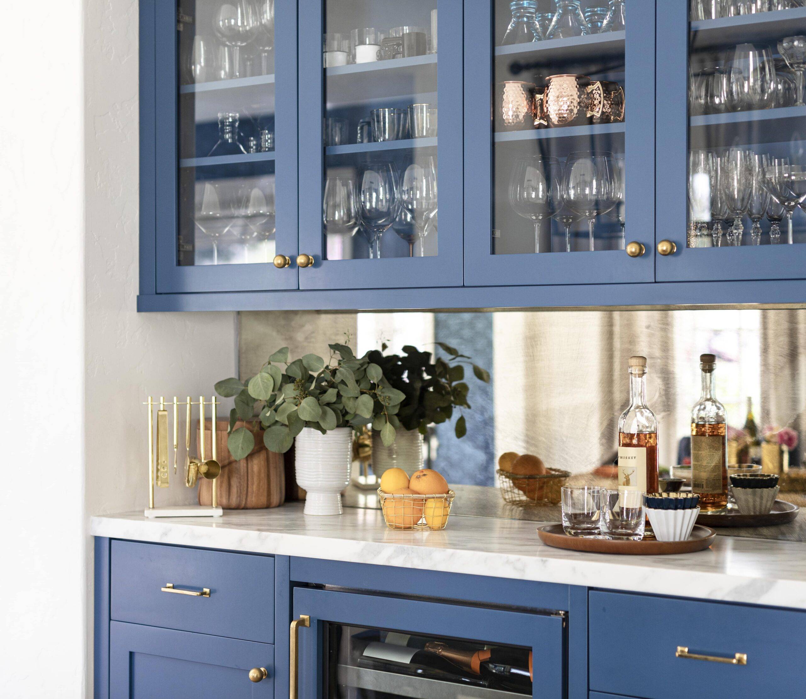Blue glass-front cabinets holding largely glassware with a white countertop.