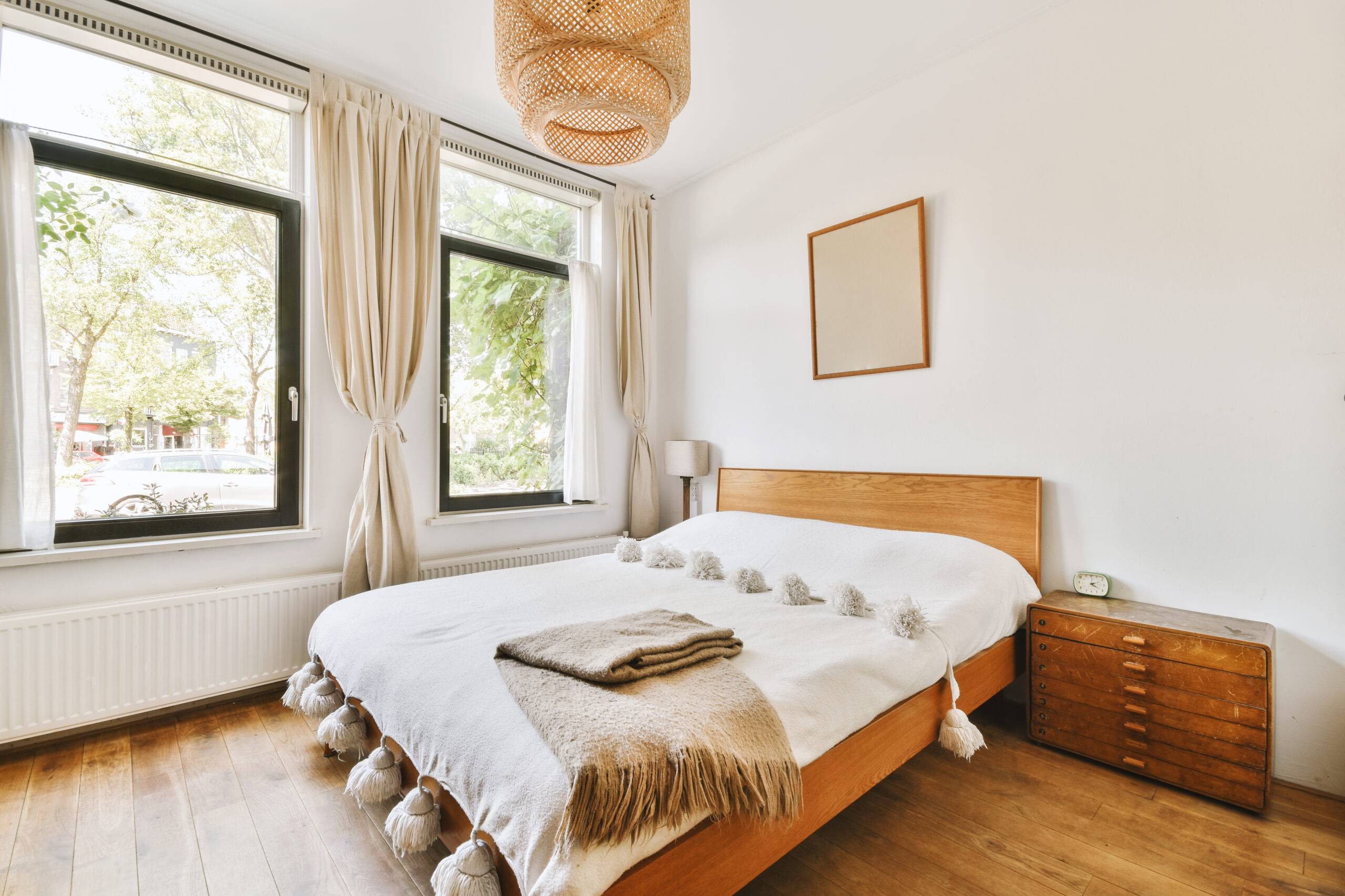 Home interior design of bedroom with bed and wooden wardrobe placed in corner near window in modern apartment