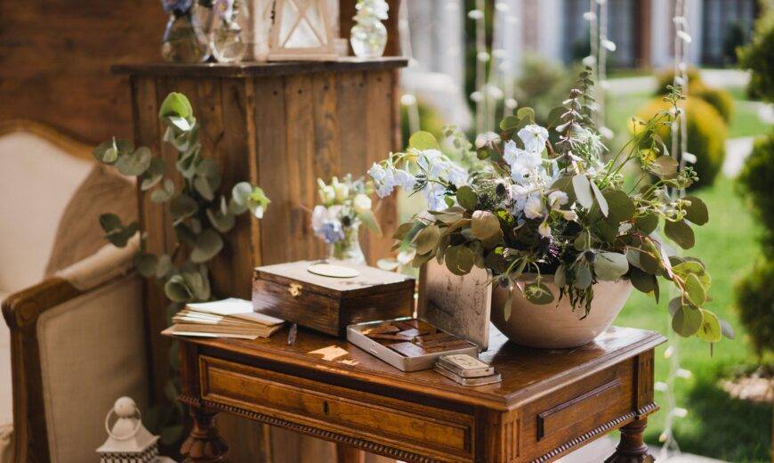 A collection of vintage decor items and greenery on a small antique table.