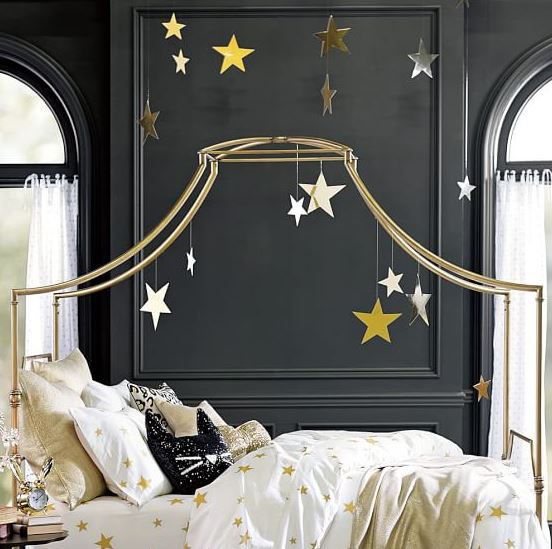 Bed with a gold frame that extends over, hanging golden stars.