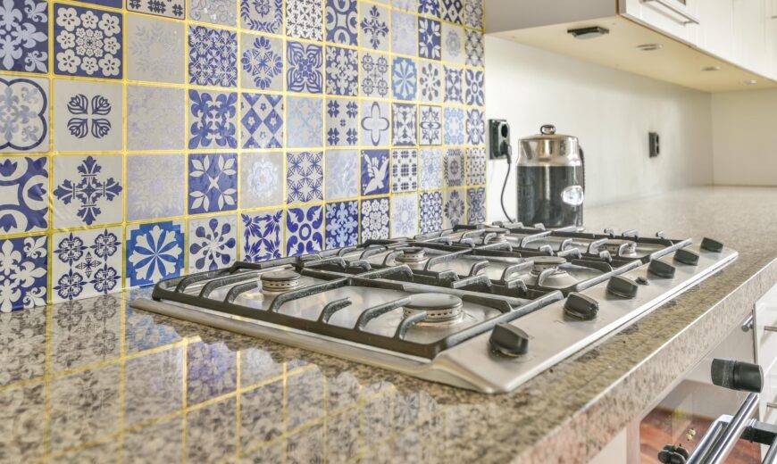 A stove with a busy tile backsplash behind it.