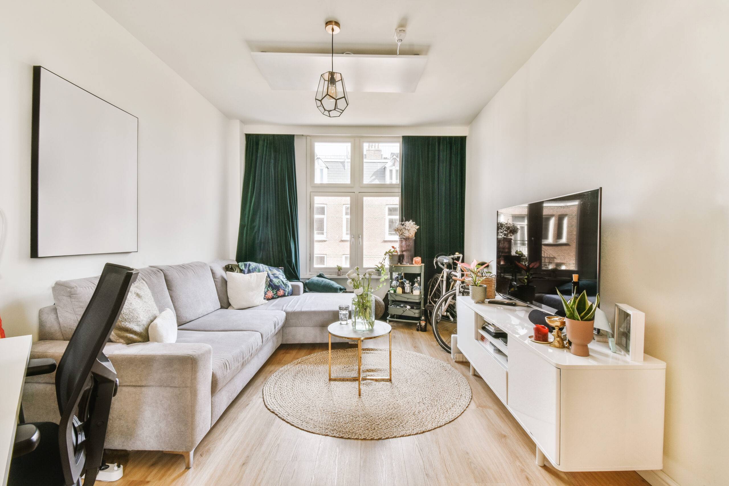 Interior of living room with comfortable sofa and TV against windows in contemporary apartment