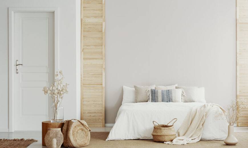 White bedroom interior with natural wooden accents and king size bed, copy space on empty wall